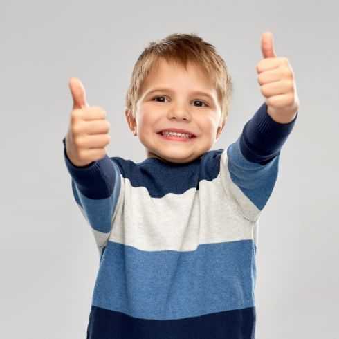 Young child smiling with thumbs up